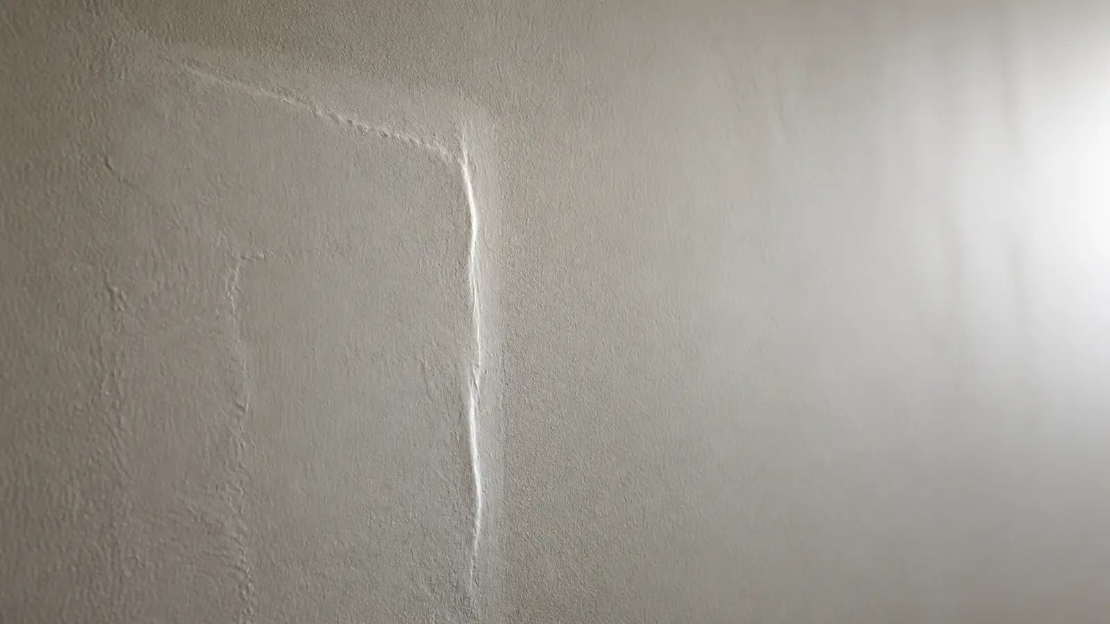 Side-lit drywall patch revealing an uneven repair ridge