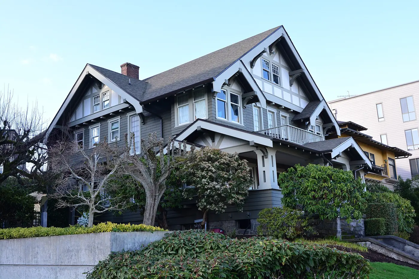 Two-story craftsman house with dark gables on a landscaped slope in Tacoma.