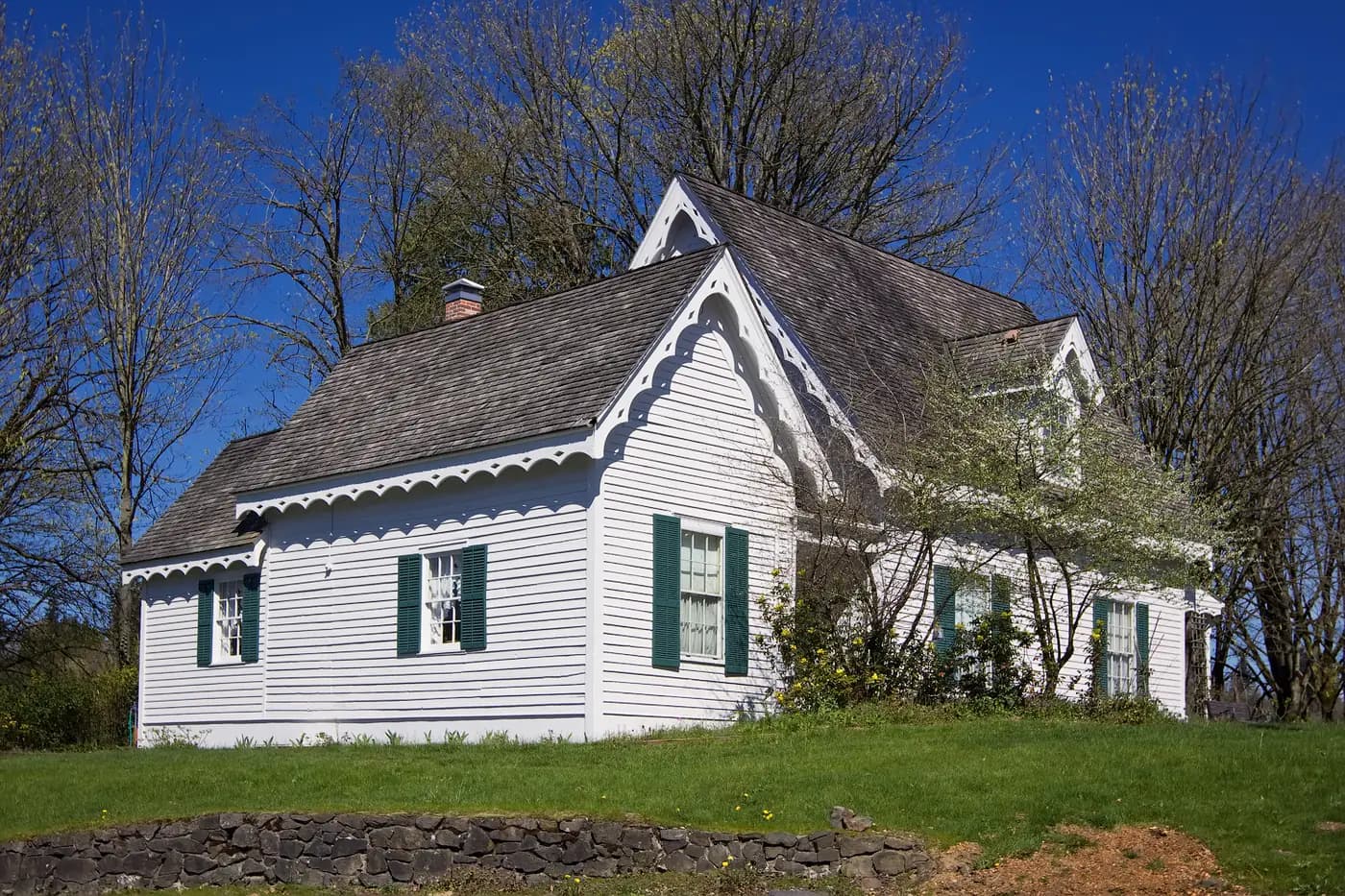 White wooden house with green shutters and a steep roof in Tumwater.