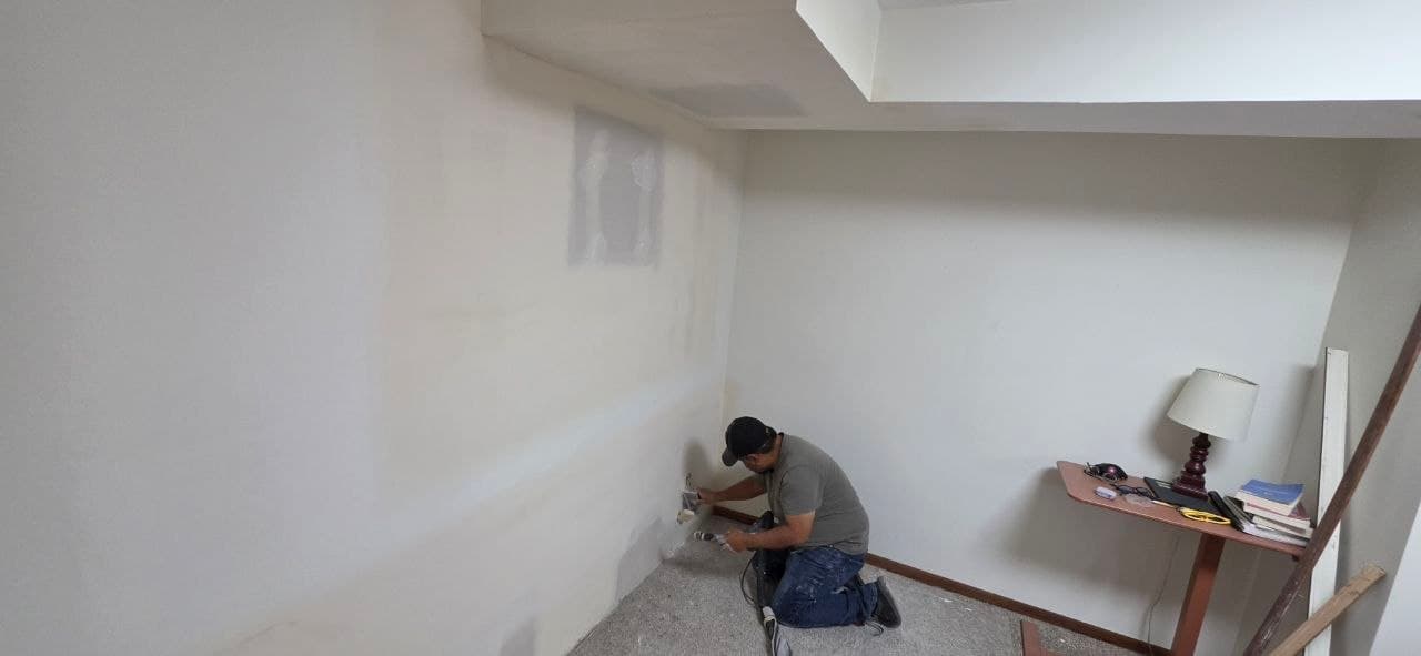 Solis Interiors worker kneeling beside the lower edge of an interior wall.