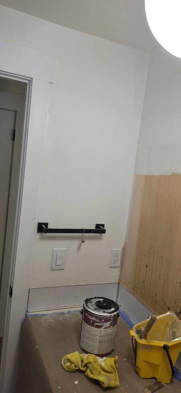Dark towel bar mounted to a bathroom wall while the adjacent wall is being finished.