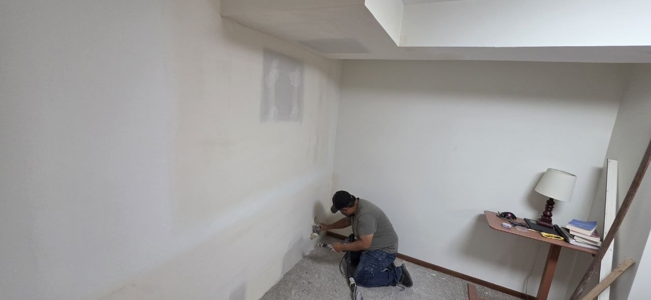 Solis Interiors worker kneeling beside the lower edge of an interior wall.